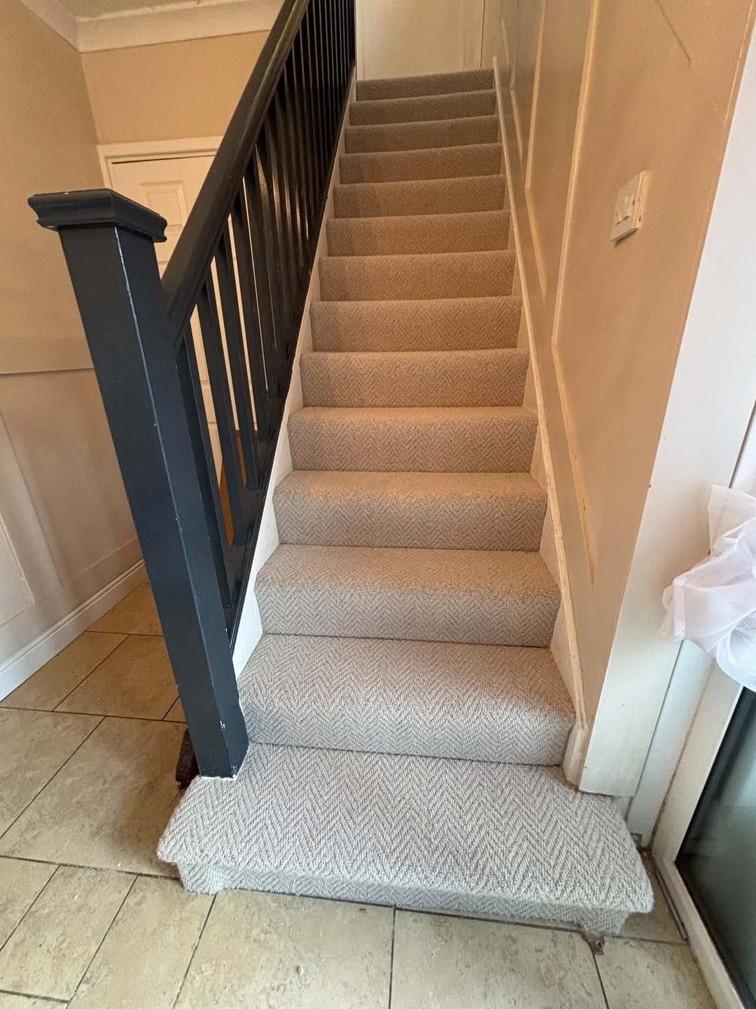 Herringbone stair carpet beside a dark painted banister