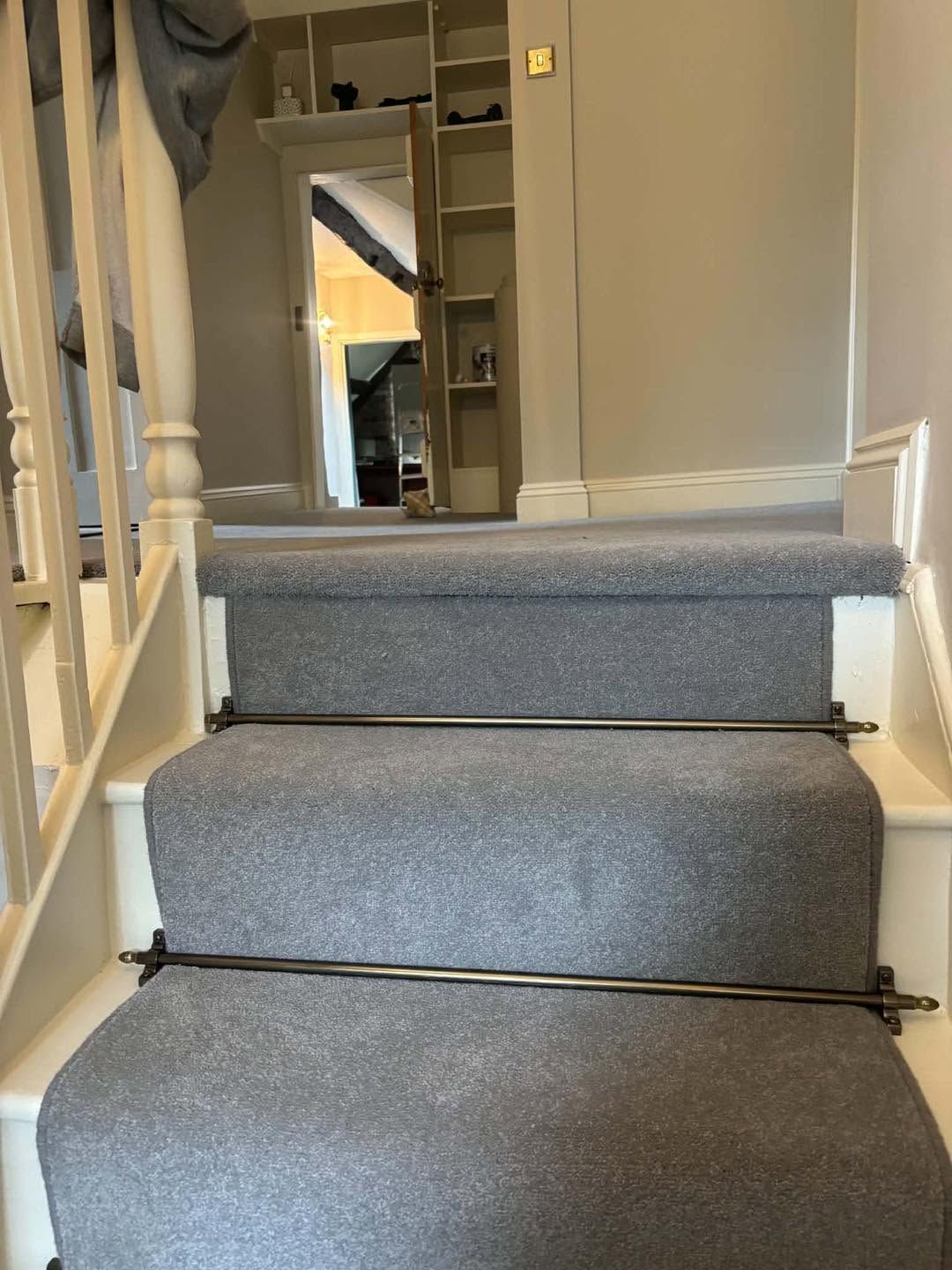 Grey carpet with stair rods fitted on a landing