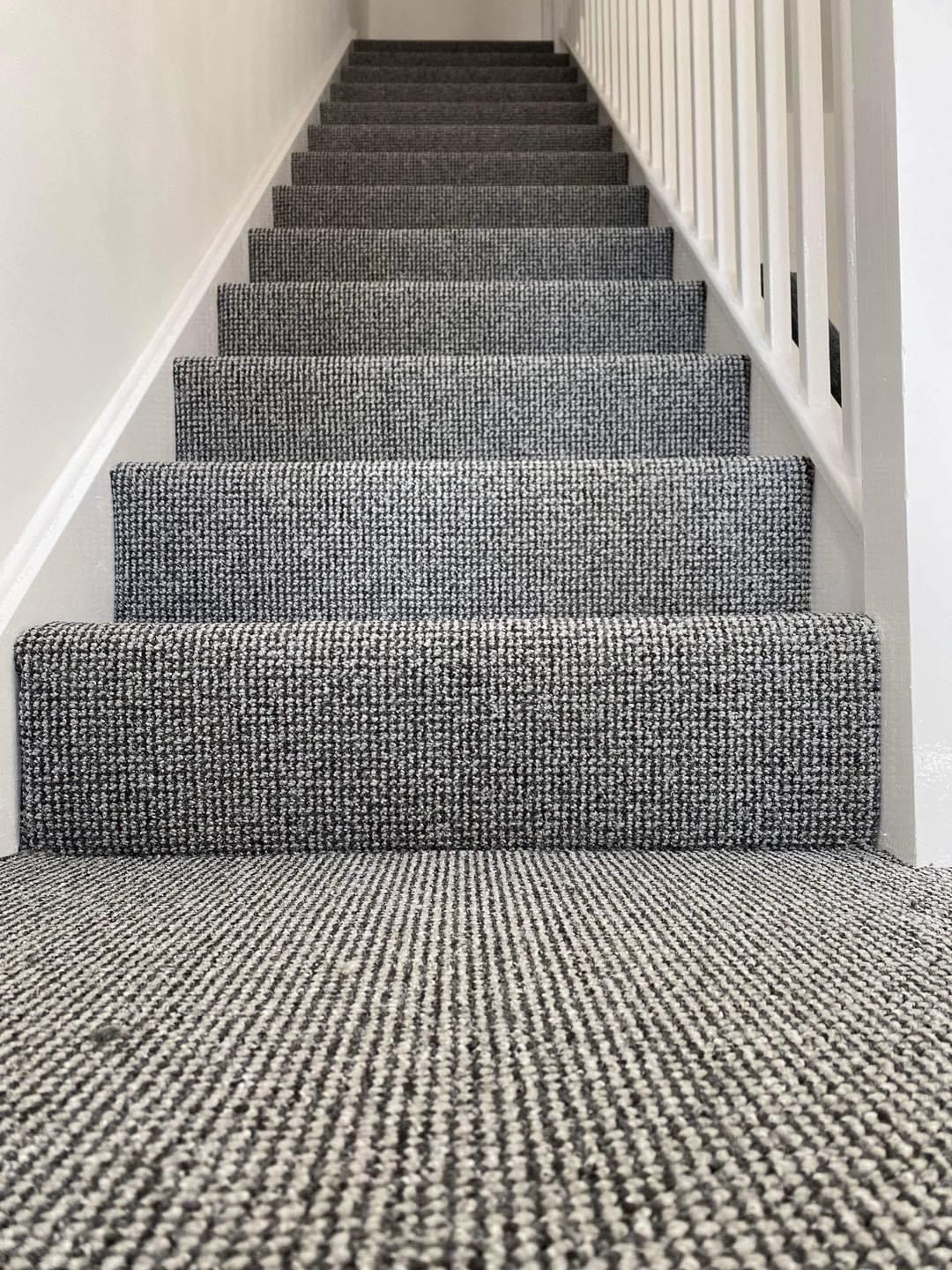 Grey stair carpet fitted up to a white landing